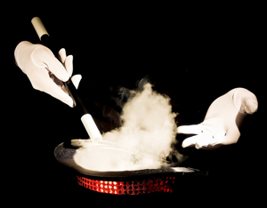 Hands of magician with wand and black hat