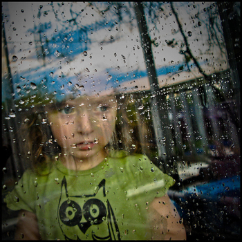 Child looking out window at rain